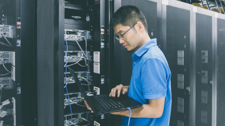 China Cybersecurity-Gesetz Mann steht mit Laptop in der Hand vor Server