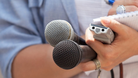 Compliance Journalistin hält Mikrofone und Aufnahmegerät und schreibt auf Papier