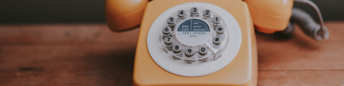 Telekommunikationsbranche orangenes Wählscheibentelefon steht auf Holztisch