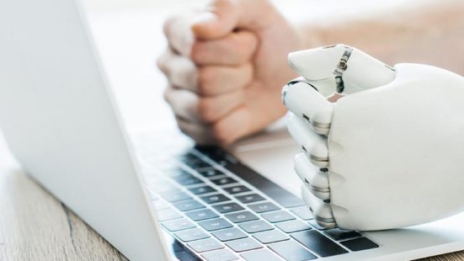 Digital Ethics eine menschliche und eine Roboterhand liegen nebeneinander auf einer Laptop-Tastatur