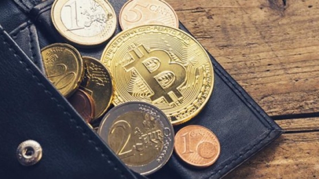 Kryptowährungen Bitcoin und Münzgeld liegen an schwarzer Brieftasche