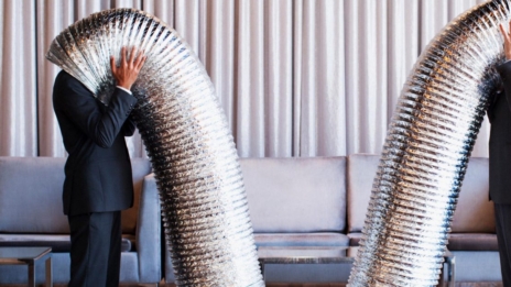 Produktentwicklung zwei Menschen in Anzügen stecken Köpfe in Aluminiumröhre