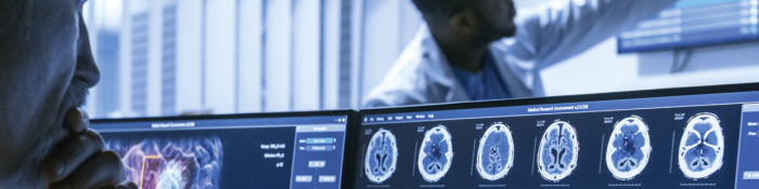 Digitalisierung Gesundheitswesen Mann in Ärztekittel blickt auf Computer mit Aufnahmen von Gehirn