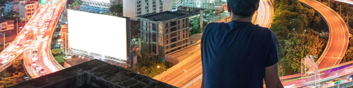 Future Readiness Mann sitzt auf Gebäude und blickt auf Skyline in der Nacht