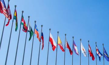 Berichterstattung Flaggen verschiedener Länder aufgereiht vor blauem Himmel