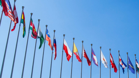 Berichterstattung Flaggen verschiedener Länder aufgereiht vor blauem Himmel