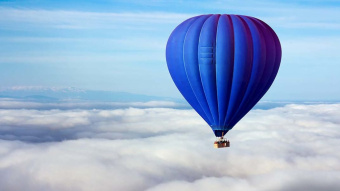 Ein blauer Heißluftballon in den Wolken.