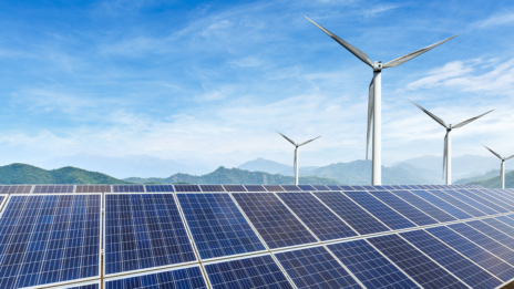 ESG: Windräder stehen hinter einer Reihe von Solarmodulen einer Photovoltaikanlage.