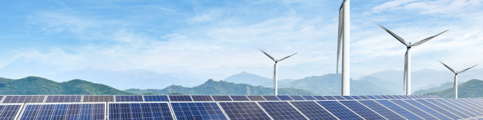 ESG: Windräder stehen hinter einer Reihe von Solarmodulen einer Photovoltaikanlage.