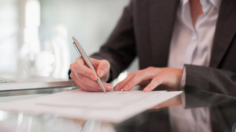 Arbeitsverträge: Eine Person unterschreibt mit einem Kugelschreiber ein Dokument.