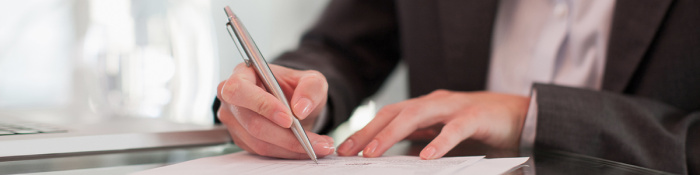 Arbeitsverträge: Eine Person unterschreibt mit einem Kugelschreiber ein Dokument.