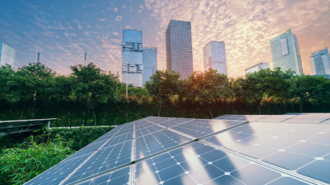 ESG: Photovoltaikanlage im Vordergrund, im Hintergrund ist vor einem Sonnenuntergangshimmel die Skyline einer Großstadt zu sehen. 