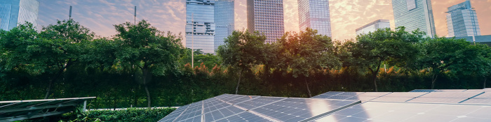 ESG: Photovoltaikanlage im Vordergrund, im Hintergrund ist vor einem Sonnenuntergangshimmel die Skyline einer Großstadt zu sehen. 