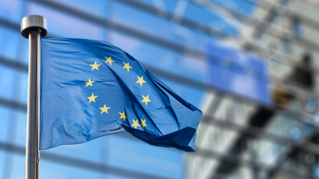 Governance & Compliance: Die Flagge der Europäischen Union, im Hintergrund Fenster eines Bürogebäudes