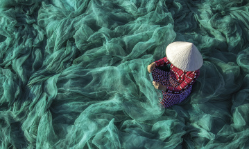 ESG, Menschenrechte: Eine Frau in Vietnam kontrolliert Fischernetze.