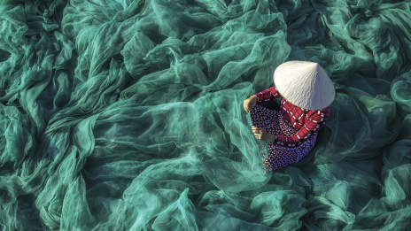 ESG, Menschenrechte: Eine Frau in Vietnam kontrolliert Fischernetze.