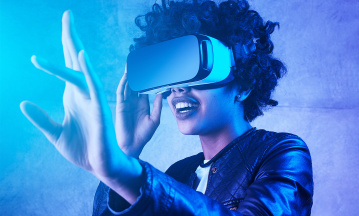 Digitale Transformation: Eine Frau bewegt sich mithilfe einer VR-Brille durch eine virtuelle Welt.