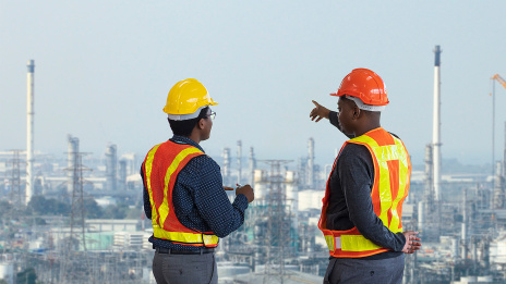 Zwei Ingenieure stehen vor großer Industrieanlage in Afrika.