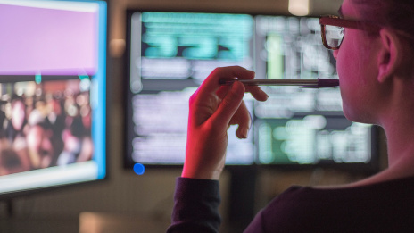 Cyber Security in Medienunternehmen: Ein IT-Mitarbeiter sitzt vor zwei Bildschirmen.