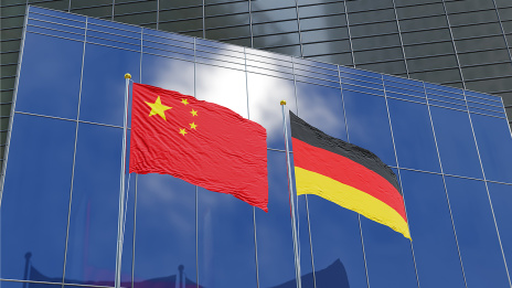 Die Flaggen von China und Deutschland wehen vor einem Bürogebäude.