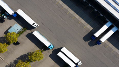 Nachhaltiger Einkauf: Mehrere Lkw stehen an einem Logistikzentrum und werden beladen