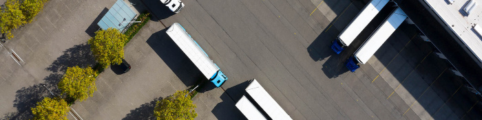 Nachhaltiger Einkauf: Mehrere Lkw stehen an einem Logistikzentrum und werden beladen