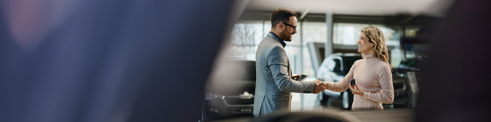 Direktvertrieb in der Automobilindustrie: Kundin erwirbt Neuwagen - Berater und Käuferin im Autohaus.