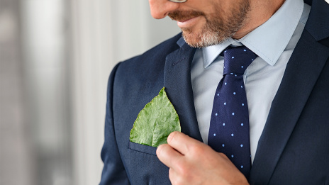 Kritik an ESG und Nachhaltigkeit: Ein Unternehmensberater steht im Büro. In der Tasche seiner Anzugsjacke steckt ein Blatt.