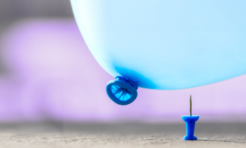 Hohes Risiko für Luftballon, der auf eine aufgestellte Nadel zuschwebt. Luftballon und Nadel nur wenige Zentimeter voneinander entfernt.