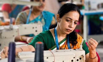 Frau arbeitet an einer Nähmaschine in einer Textilfabrik