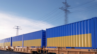 Blaue und gelbe Güterwaggons auf Schienen vor blauem Himmel.