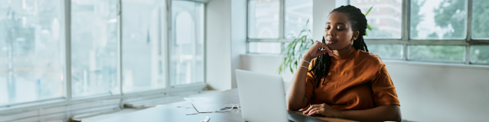 Umsatzsteuer im Fokus: Eine Mitarbeiterin eines Unternehmens bearbeitet im Büro an einem Laptop Steuerunterlagen. 