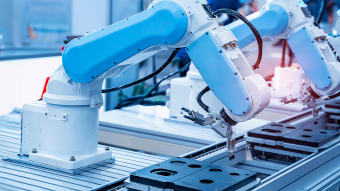 Smart Factory. Ein Roboterarm montiert etwas in einer Fabrik. 