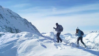 Bergwelt, ähnlich der in Davos. Zwei Bergwanderer sind dort zu sehen, wie sie in Richtung Bergspitze wandern. 