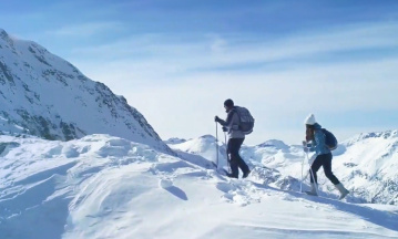 Bergwelt, ähnlich der in Davos. Zwei Bergwanderer sind dort zu sehen, wie sie in Richtung Bergspitze wandern. 