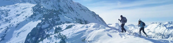 Bergwelt, ähnlich der in Davos. Zwei Bergwanderer sind dort zu sehen, wie sie in Richtung Bergspitze wandern. 