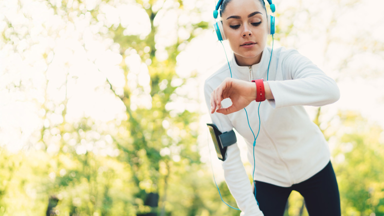 Symbolbild zum Data Act: Joggerin mit Kopfhörern schaut auf ihr Fitnessarmband.