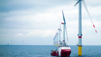 Ein Frachtschiff fährt an Offshore-Anlagen vorbei