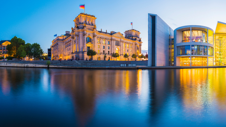 Der Bundestag in Berlin. Aufnahme mit blauem Himmel, durch die nächtliche Atmosphäre auf dem Bild, kommt die Beleuchtung des Bundestags und des Paul-Löbe-Hauses besonders zur Geltung.