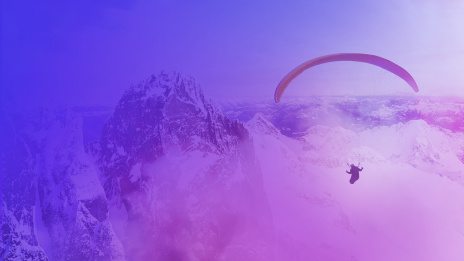 Mann fliegt mit einem Paraglide über eine Berglandschaft