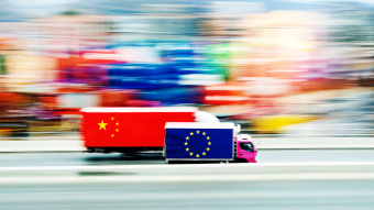 Zwei LKW nebeneinander. Einer mit einer europäischen Flagge, einer mit einer chinesischen. Der mit der europäischen Flagge liegt leicht in Führung. 