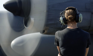 Eine Soldatin inspiziert ein kürzlich repariertes Flugzeug des Typs Lockheed C-130.