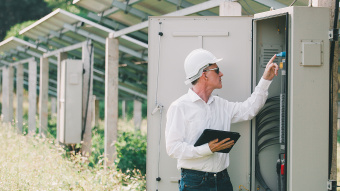 Mann prüft Anschlüsse an einem Sicherungskasten für Solaranlagen
