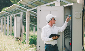 Mann prüft Anschlüsse an einem Sicherungskasten für Solaranlagen