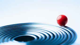 Rote Kugel liegt auf blauen konzentrischen Kreisen und symbolisiert Balance, Fokus und ganzheitliche Unternehmens-Performance.