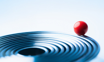 Rote Kugel liegt auf blauen konzentrischen Kreisen und symbolisiert Balance, Fokus und ganzheitliche Unternehmens-Performance.