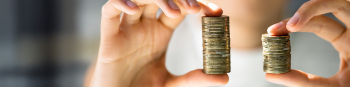 Symbolbild zur Entgelttransparenzrichtlinie: Person hält zwei ungleiche Stapel mit Münzen in den Händen