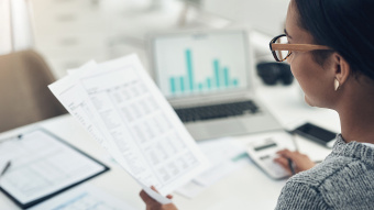 Frau prüft Gehaltsabrechnung an einem Schreibtisch.