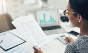 Frau prüft Gehaltsabrechnung an einem Schreibtisch.