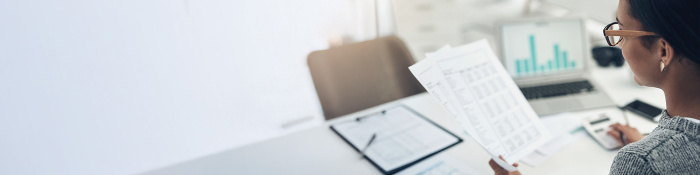 Frau prüft Gehaltsabrechnung an einem Schreibtisch.